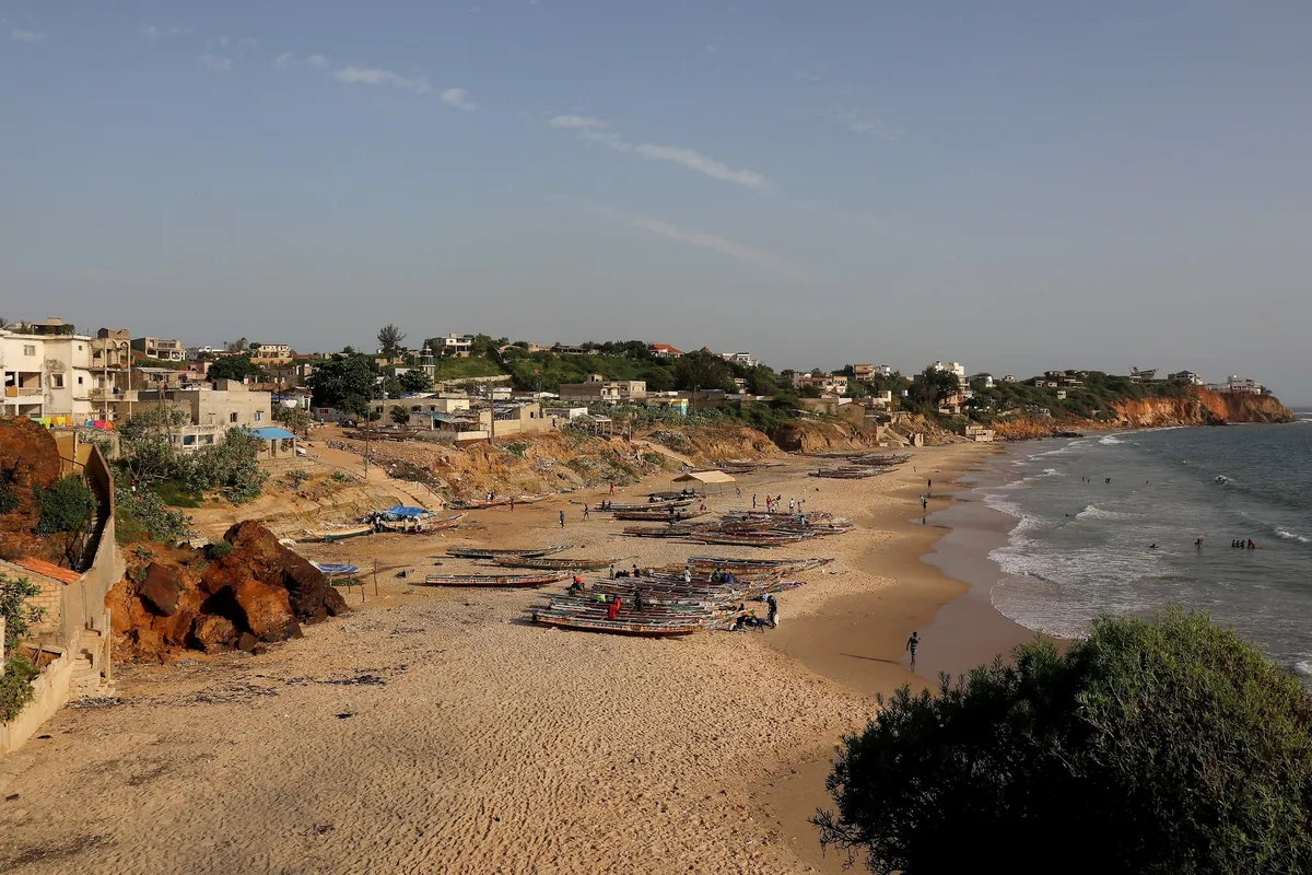 La plage de Toubab Dialaw avec ses pirogues et le village posé sur la falaise