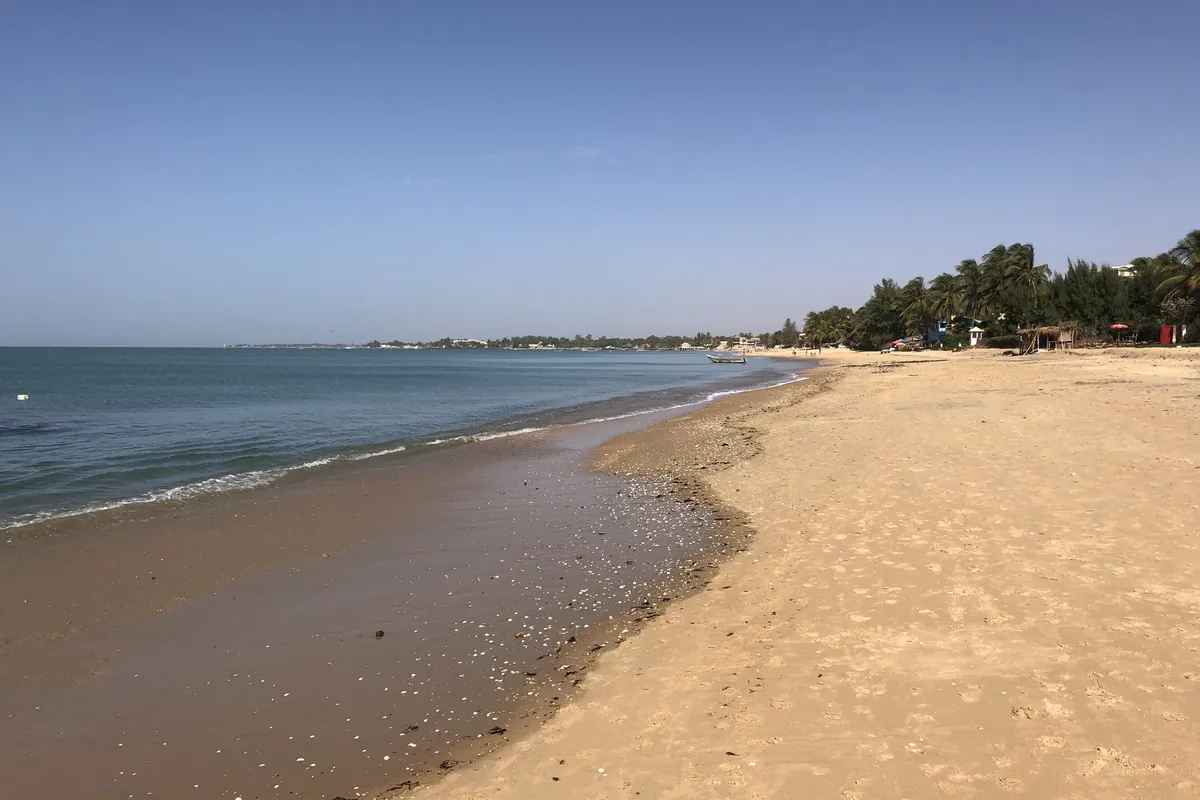 La longue plage de sable de Saly Portudal, avec des palmiers au loin